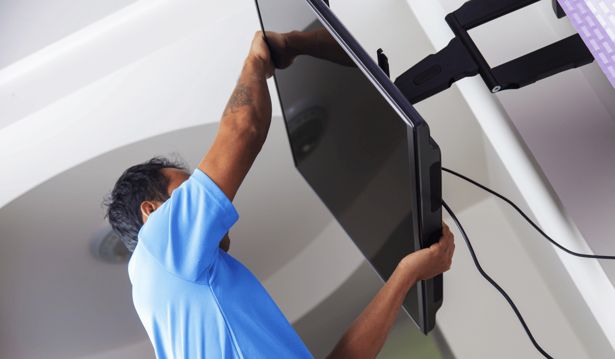 A man expertly fixing a flat screen television on a wall mount in Altona